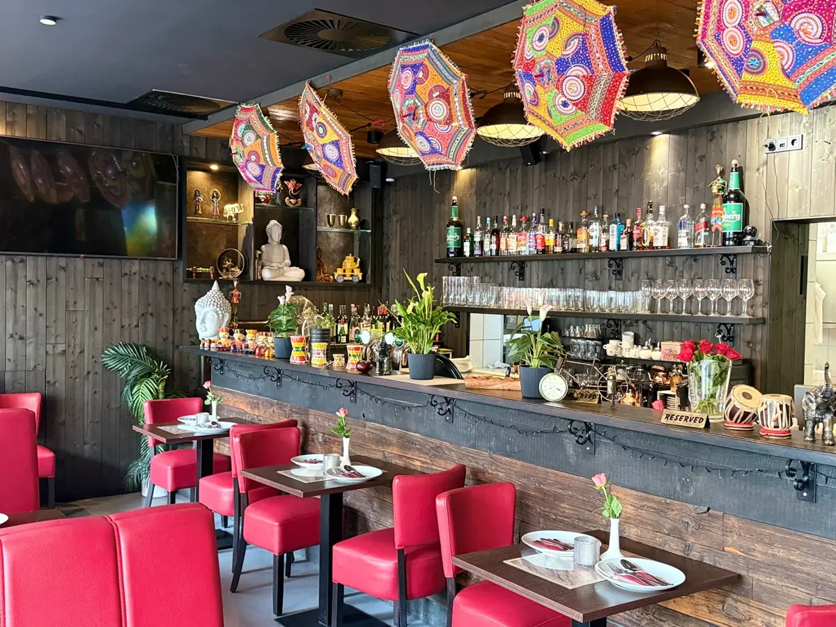 Der Gastraum von Mumbai Masala mit bunten Schirmen und roten Stühlen